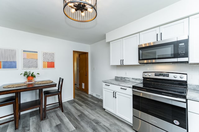 311 Wisconsin St, Lake City, MN 55041 - kitchen featuring appliances with stainless steel finishes, backsplash, white cabinetry, wood finished floors, and baseboards