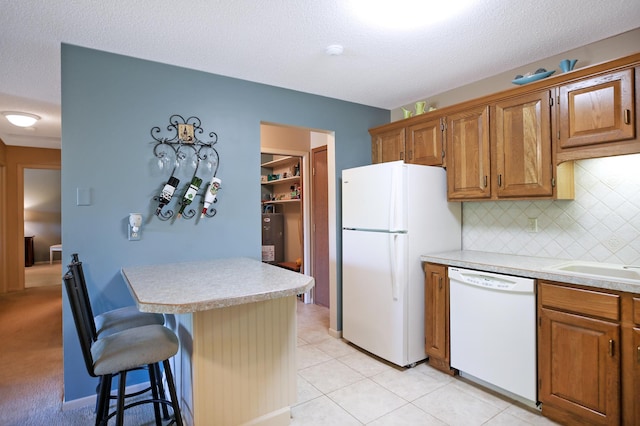1825 Perlich Ave Unit 206, Red Wing, MN 55066 - kitchen featuring white appliances, a breakfast bar area, light countertops, decorative backsplash, and brown cabinets