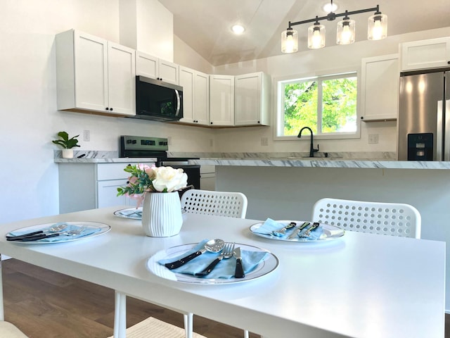 826 Sims Ave, Saint Paul, MN 55106 - kitchen featuring appliances with stainless steel finishes, light countertops, vaulted ceiling, white cabinetry, and a breakfast bar area