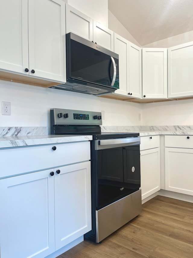826 Sims Ave, Saint Paul, MN 55106 - kitchen featuring stainless steel appliances, lofted ceiling, white cabinets, and wood finished floors