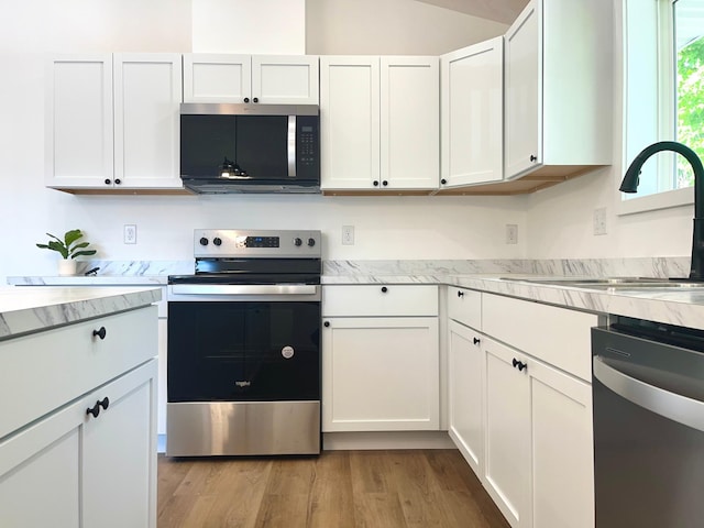 826 Sims Ave, Saint Paul, MN 55106 - kitchen with appliances with stainless steel finishes, a sink, white cabinetry, and light wood-type flooring
