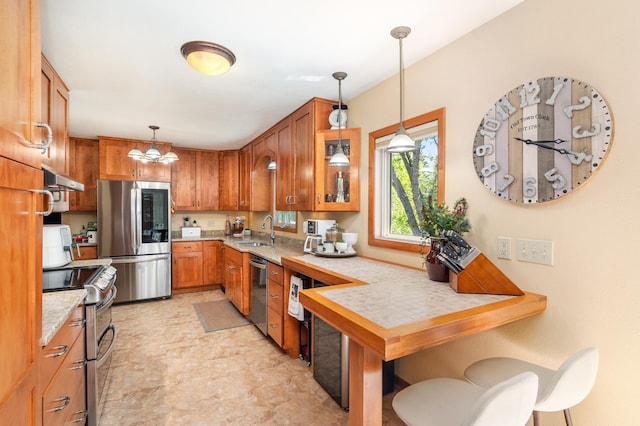721 Maple Dr, Aurora, MN 55705 - kitchen featuring stainless steel appliances, a sink, light countertops, brown cabinetry, and hanging light fixtures