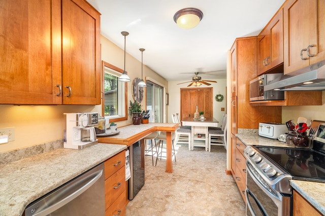 721 Maple Dr, Aurora, MN 55705 - kitchen featuring appliances with stainless steel finishes, brown cabinetry, a ceiling fan, hanging light fixtures, and under cabinet range hood