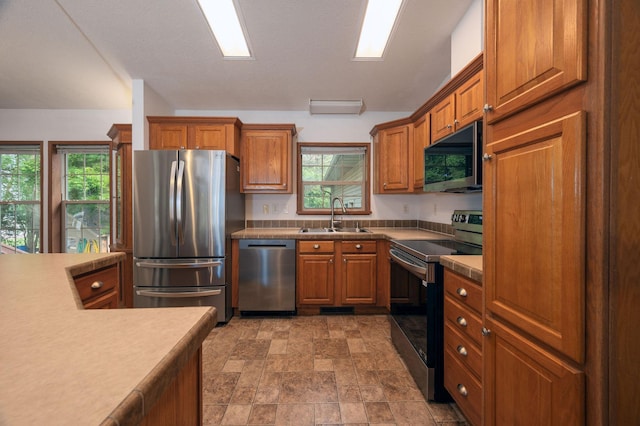 614 S Shore Dr S, Windom, MN 56101 - kitchen with appliances with stainless steel finishes, a sink, brown cabinets, stone finish floors, and healthy amount of natural light