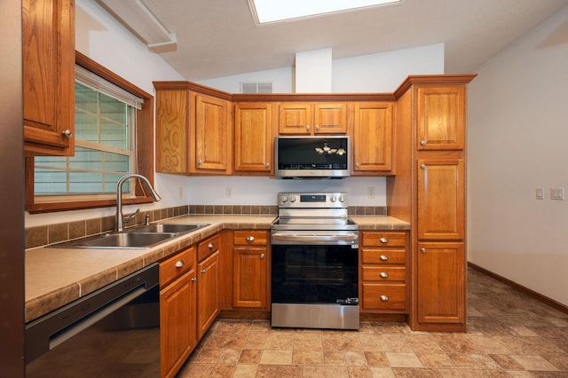 614 S Shore Dr S, Windom, MN 56101 - kitchen featuring appliances with stainless steel finishes, a sink, brown cabinets, lofted ceiling, and stone finish floors