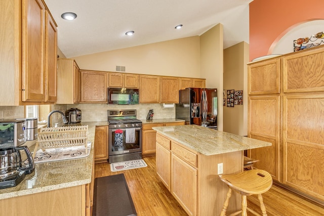28610 Bay Shore Dr NW, Isanti, MN 55040 - kitchen featuring black appliances, vaulted ceiling, tasteful backsplash, light stone countertops, and light wood-style flooring