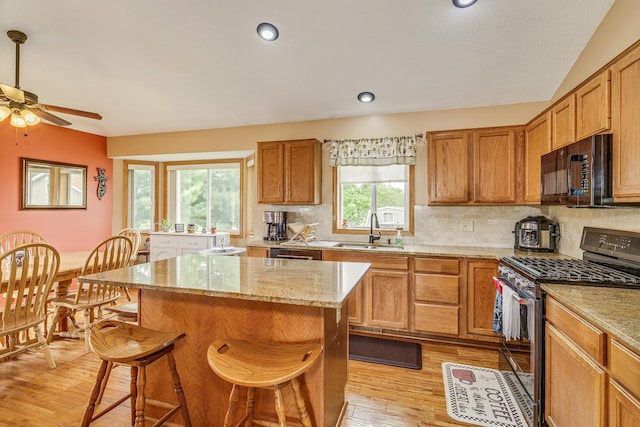 28610 Bay Shore Dr NW, Isanti, MN 55040 - kitchen featuring appliances with stainless steel finishes, a sink, light wood-style floors, a kitchen breakfast bar, and a center island