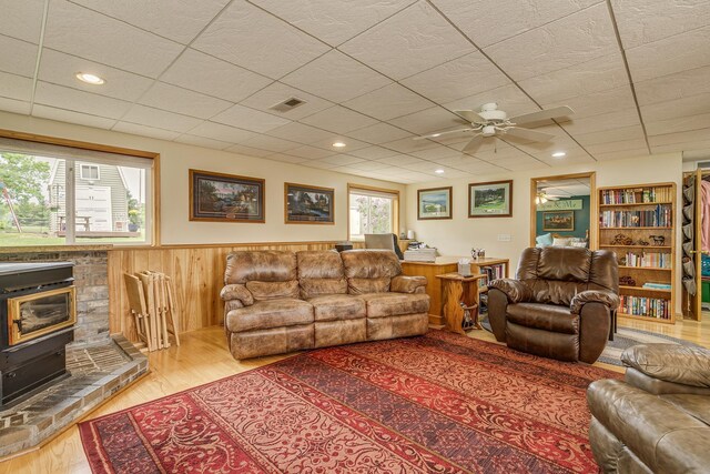 28610 Bay Shore Dr NW, Isanti, MN 55040 - living area featuring a wainscoted wall, a ceiling fan, wood finished floors, a wood stove, and wooden walls