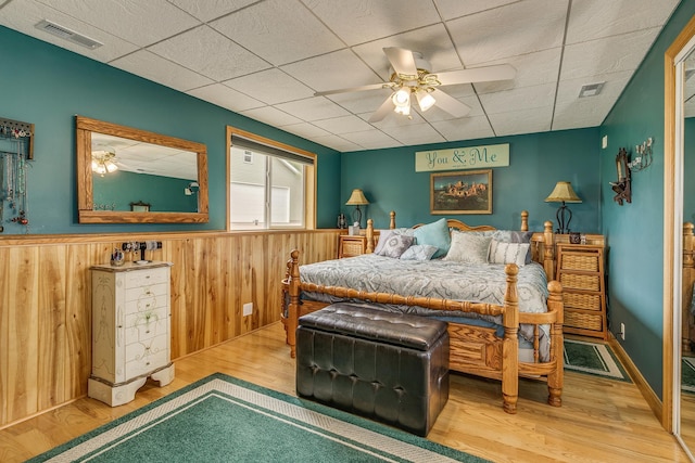 28610 Bay Shore Dr NW, Isanti, MN 55040 - bedroom featuring wood finished floors, a wainscoted wall, a paneled ceiling, wood walls, and a ceiling fan
