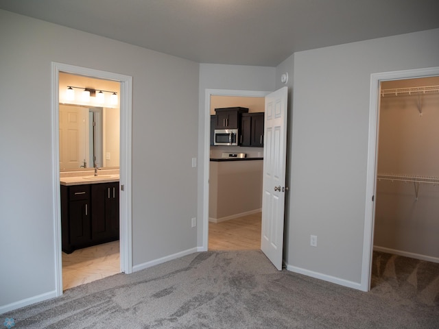 6325 83rd Ave S, Horace, ND 58047 - unfurnished bedroom with a spacious closet, light carpet, a sink, a closet, and baseboards