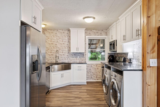 218 9 1/4 Ave, Turtle Lake, WI 54004 - kitchen featuring stainless steel appliances, a sink, washer and dryer, dark countertops, and white cabinets