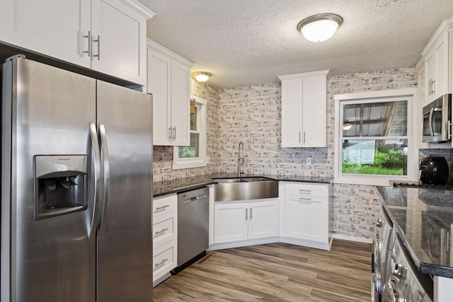 218 9 1/4 Ave, Turtle Lake, WI 54004 - kitchen with appliances with stainless steel finishes, a sink, white cabinets, wood finished floors, and a textured ceiling