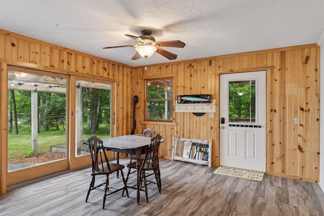 218 9 1/4 Ave, Turtle Lake, WI 54004 - dining room featuring ceiling fan, wood finished floors, wooden walls, and a textured ceiling