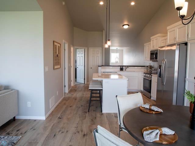 6321 83rd Ave S, Horace, ND 58047 - kitchen with stainless steel appliances, a peninsula, white cabinetry, a breakfast bar, and light wood-style floors