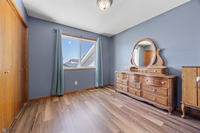 1095 Parkway Ln, West Fargo, ND 58078 - bedroom with wood finished floors, a textured ceiling, baseboards, and a closet