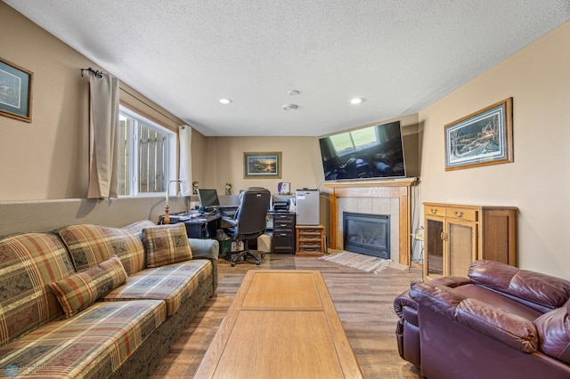1095 Parkway Ln, West Fargo, ND 58078 - living room with wood finished floors, a textured ceiling, a tiled fireplace, recessed lighting, and a desk