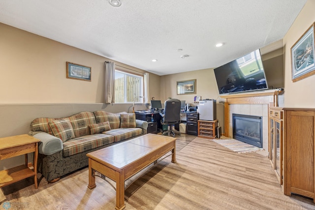 1095 Parkway Ln, West Fargo, ND 58078 - living area with light wood-type flooring, a textured ceiling, a tiled fireplace, and an office area
