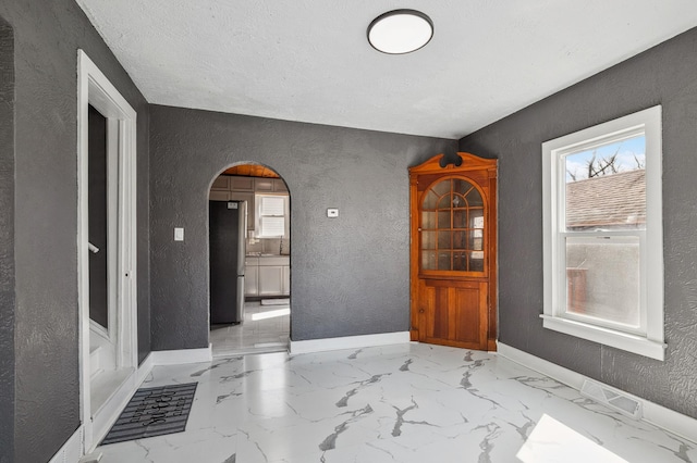 1010 8th Ave NE, Austin, MN 55912 - foyer entrance featuring a textured wall, arched walkways, baseboards, and marble finish floors