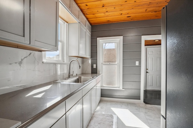 1010 8th Ave NE, Austin, MN 55912 - kitchen featuring a sink, light marble finish floors, wooden ceiling, backsplash, and white cabinets
