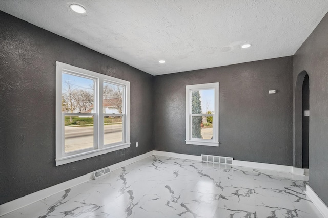 1010 8th Ave NE, Austin, MN 55912 - empty room featuring arched walkways, baseboards, a textured wall, recessed lighting, and a textured ceiling