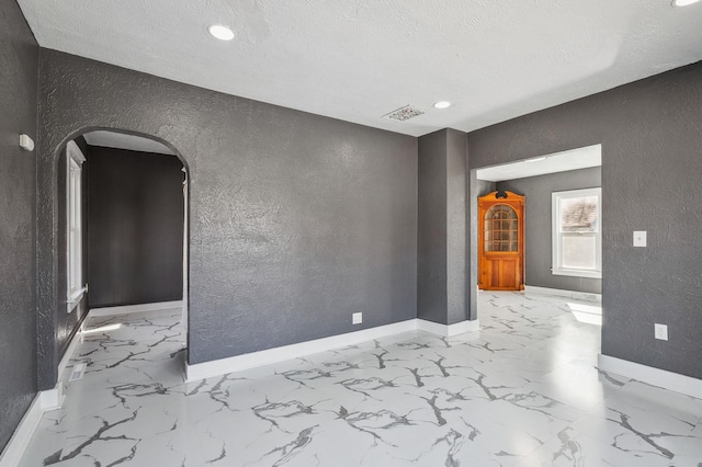 1010 8th Ave NE, Austin, MN 55912 - unfurnished room with a textured wall, baseboards, arched walkways, marble finish floors, and recessed lighting