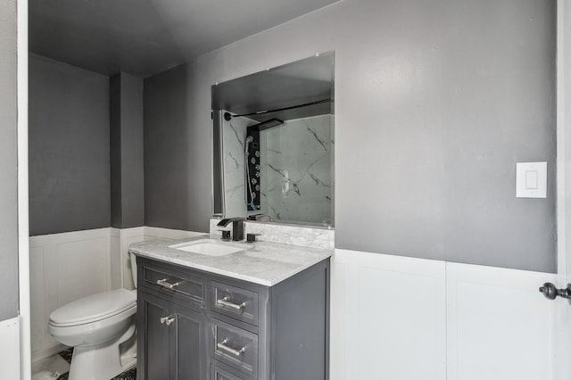 1010 8th Ave NE, Austin, MN 55912 - bathroom featuring toilet, vanity, a wainscoted wall, a marble finish shower, and a decorative wall