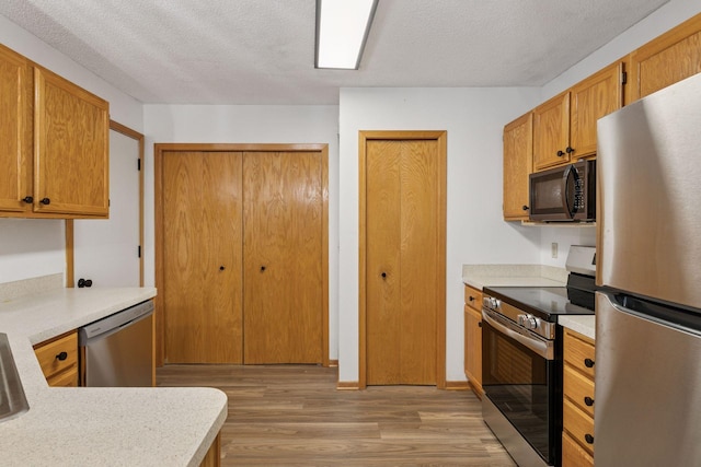 8379 Corcoran Cir Unit 47, Inver Grove Heights, MN 55076 - kitchen featuring stainless steel appliances, light wood-style floors, light countertops, a textured ceiling, and brown cabinets