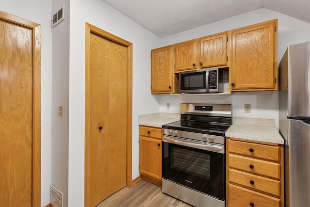 8379 Corcoran Cir Unit 47, Inver Grove Heights, MN 55076 - kitchen with appliances with stainless steel finishes, light wood-style flooring, light countertops, a textured ceiling, and vaulted ceiling