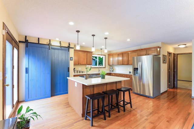 10432 102nd Pl, Maple Grove, MN 55369 - kitchen with stainless steel appliances, light wood-style flooring, a center island, light countertops, and a breakfast bar
