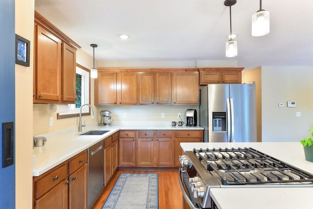 10432 102nd Pl, Maple Grove, MN 55369 - kitchen with stainless steel appliances, a sink, hanging light fixtures, light wood finished floors, and light countertops