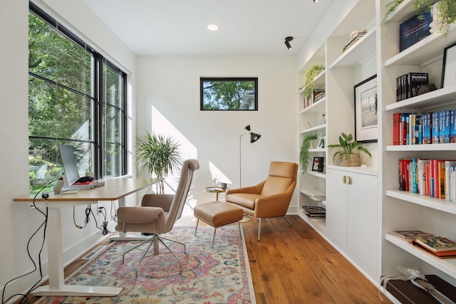 sitting room featuring an office area, wood finished floors, built in shelves, and recessed lighting