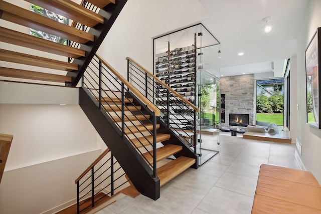 stairs with a stone fireplace, tile patterned flooring, and baseboards