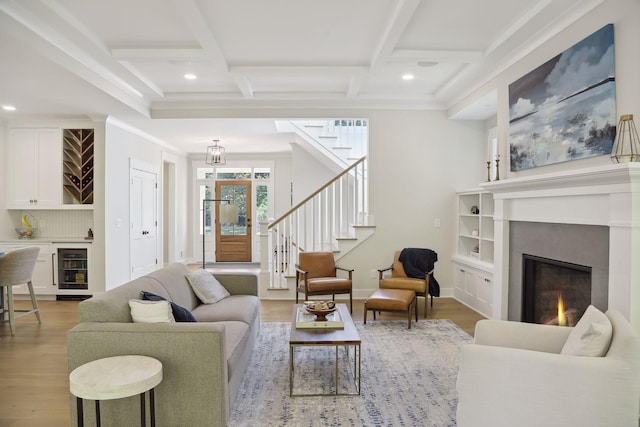 living area featuring wine cooler, wood finished floors, stairs, beamed ceiling, and coffered ceiling