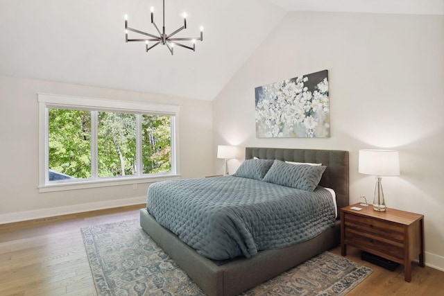 bedroom with a chandelier, vaulted ceiling, wood finished floors, and baseboards