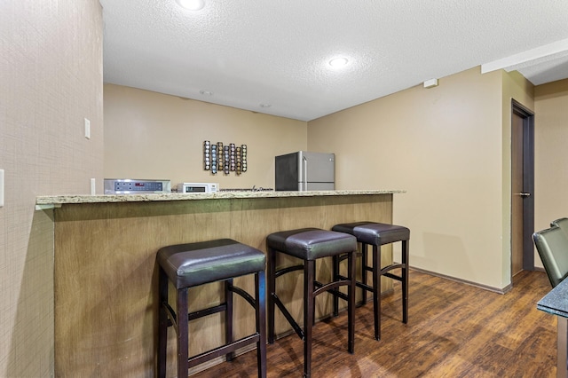 10441 Greenbrier Rd Unit 315, Minnetonka, MN 55305 - indoor dry bar with freestanding refrigerator, dark wood-style floors, a textured ceiling, baseboards, and white microwave
