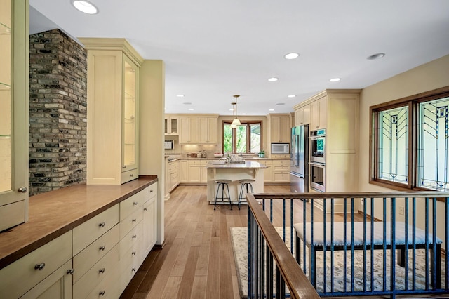 451 Reflection Rd, Apple Valley, MN 55124 - kitchen with appliances with stainless steel finishes, light wood finished floors, a kitchen island, a breakfast bar area, and recessed lighting
