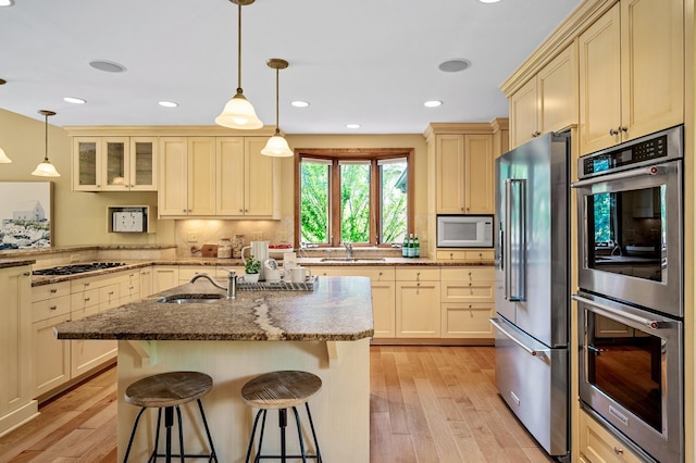 451 Reflection Rd, Apple Valley, MN 55124 - kitchen featuring stainless steel appliances, light wood finished floors, a kitchen breakfast bar, light stone counters, and recessed lighting