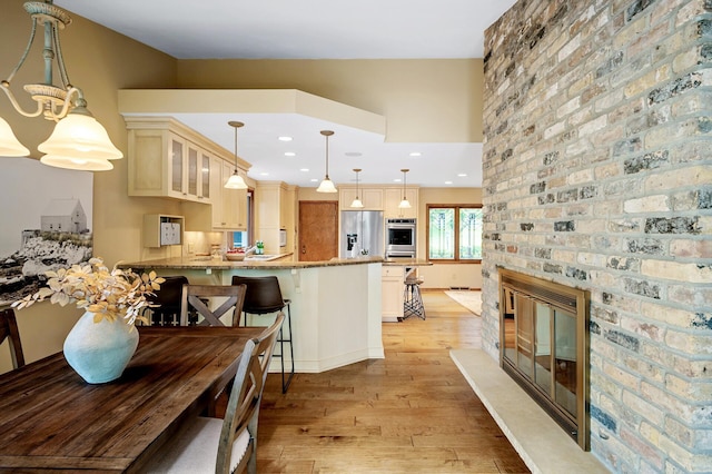 451 Reflection Rd, Apple Valley, MN 55124 - kitchen with appliances with stainless steel finishes, light wood-style flooring, glass insert cabinets, light stone counters, and a peninsula
