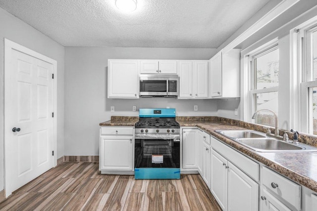1912 15th Ave N, Minneapolis, MN 55411 - kitchen featuring stainless steel appliances, a sink, white cabinets, a textured ceiling, and light wood-style flooring