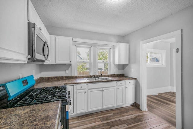 1912 15th Ave N, Minneapolis, MN 55411 - kitchen featuring stainless steel appliances, a sink, dark countertops, white cabinetry, and a textured ceiling