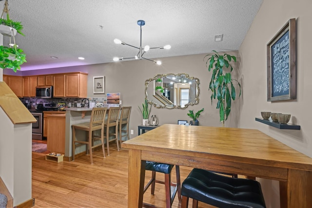 367 Ojibway Path, Lino Lakes, MN 55014 - dining space featuring a textured ceiling, light wood-style floors, and a chandelier