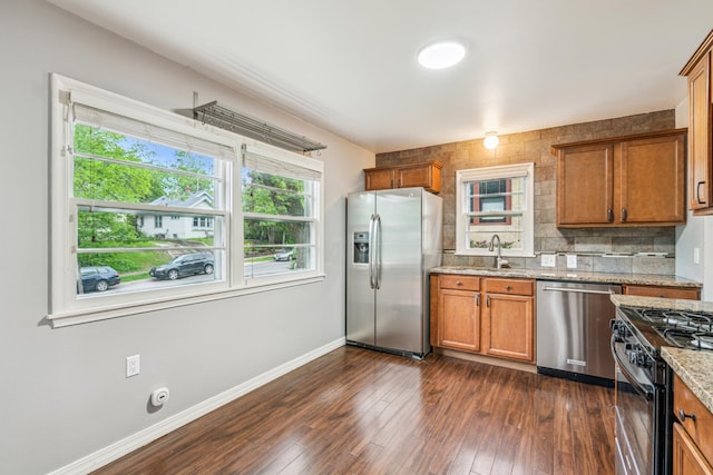 3945 15th Ave S, Minneapolis, MN 55407 - kitchen with appliances with stainless steel finishes, brown cabinets, baseboards, light stone counters, and dark wood-style flooring
