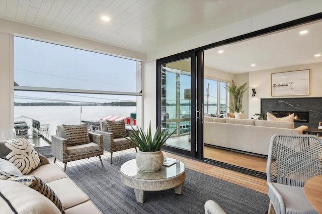 living room with a fireplace, recessed lighting, wood finished floors, and a water view