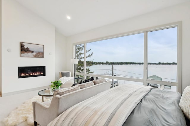 bedroom with a water view, a glass covered fireplace, lofted ceiling, and recessed lighting