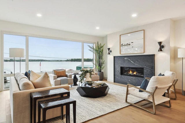 living room with a fireplace, wood finished floors, recessed lighting, a water view, and baseboards
