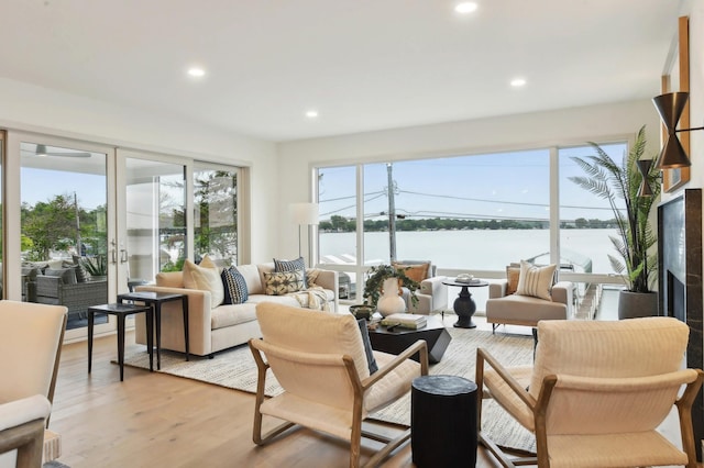 living room with recessed lighting, light wood finished floors, and a water view