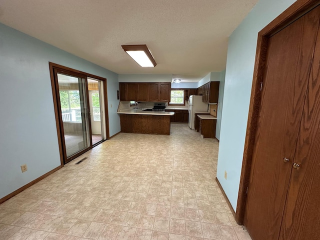 14390 Sperry Lake Rd, Harrison Twp, MN 56209 - kitchen featuring freestanding refrigerator, a peninsula, light countertops, baseboards, and a textured ceiling