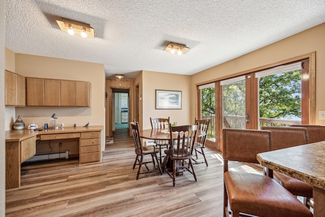 12975 185th St, Cold Spring, MN 56320 - dining space with a baseboard heating unit, light wood finished floors, a textured ceiling, and a desk