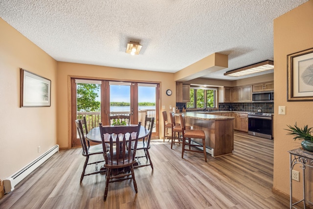 12975 185th St, Cold Spring, MN 56320 - dining area with a baseboard radiator, light wood-style flooring, a textured ceiling, a water view, and baseboards