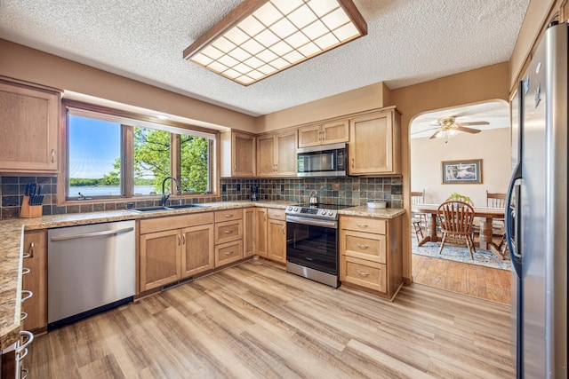 12975 185th St, Cold Spring, MN 56320 - kitchen featuring stainless steel appliances, a sink, a textured ceiling, light wood-style flooring, and tasteful backsplash